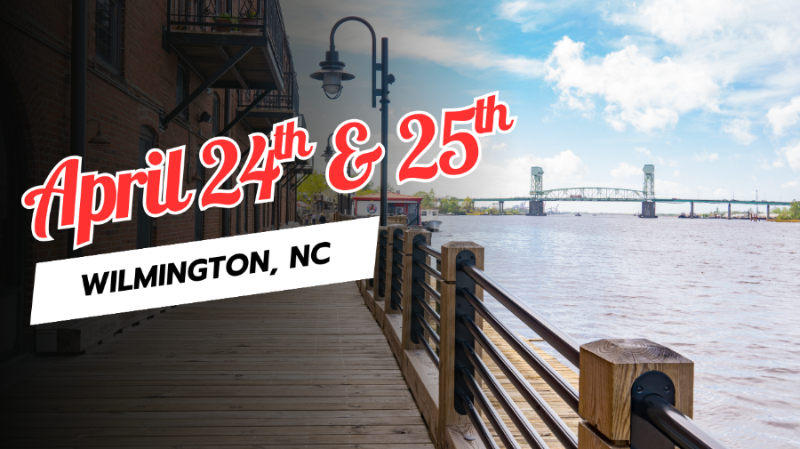 A riverwalk looking out onto a body of water and a large bridge.